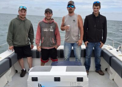 Four men are standing together and posing on a boat in the middle of the ocean